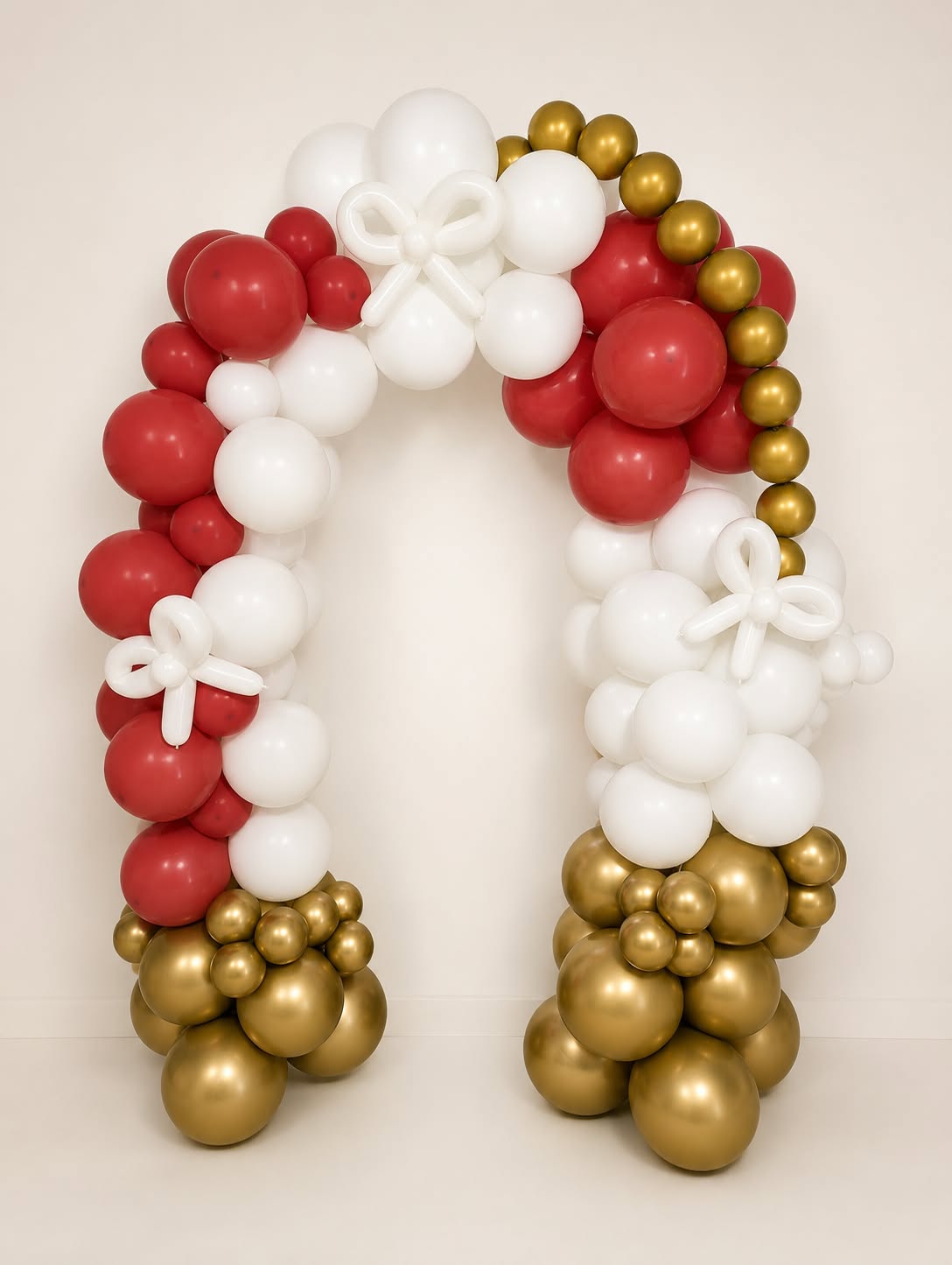 Air & Glow red, white and gold birthday balloon arch with bow details